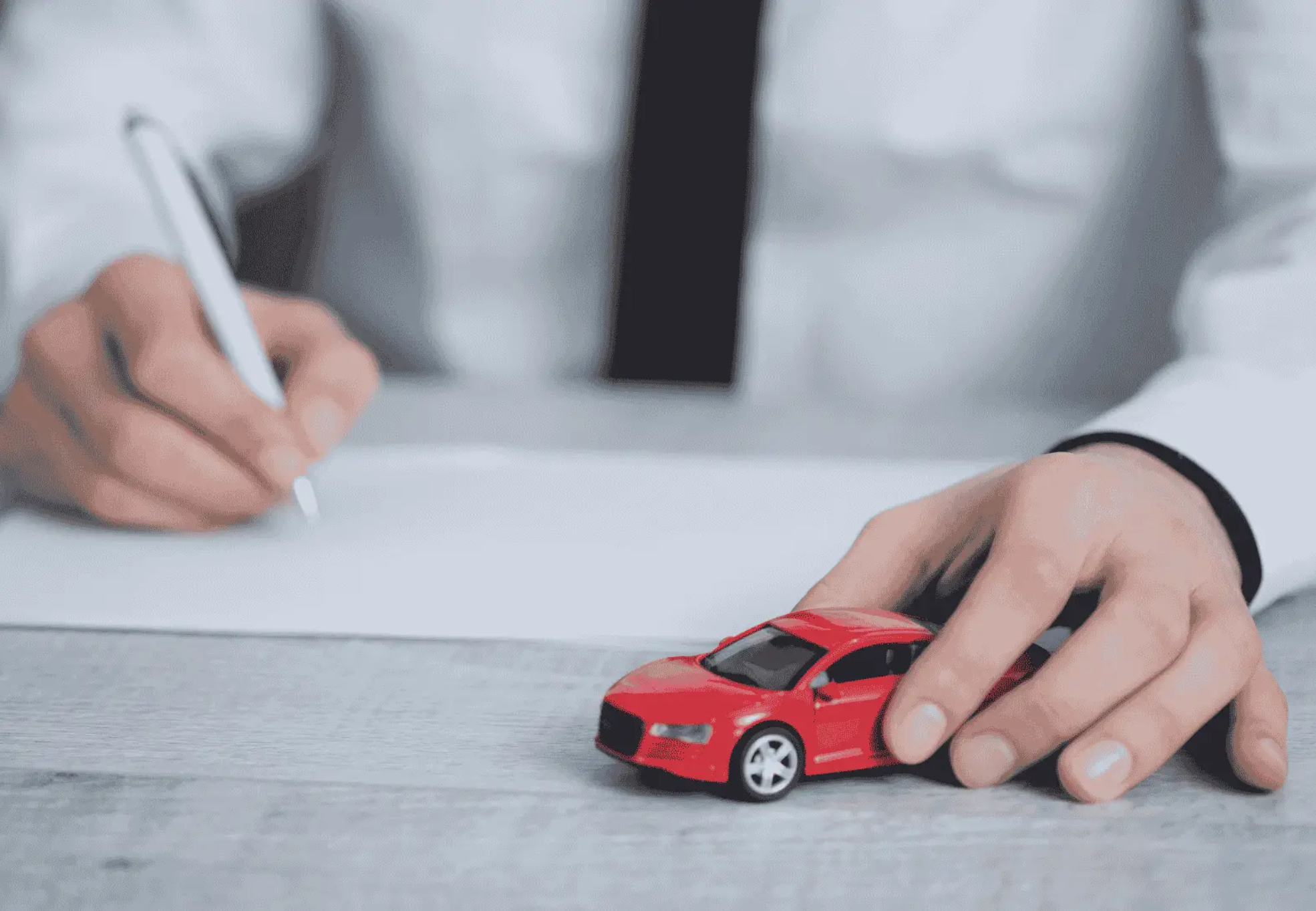 Person signing PCP claim form while holding toy car, showing how long does a PCP claim take.